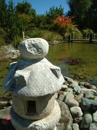 A stone sculpture next to a pond. 