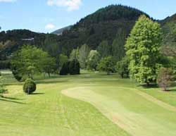 A fairway overlooking trees and green hills. 