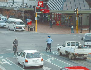 A cyclist stopped at an intersection amongst cars. 